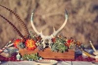 13 a wooden box centerpiece with bold blooms, succulents, feathers and a skull for a boho wedding