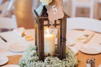 13 a wooden candle lantern with a white rose and a table number on top, a floral and foliage pad looks cute and rustic