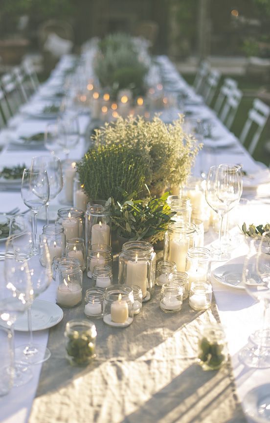 multiple jars with candles, potted herbs and greenery and a burlap runner