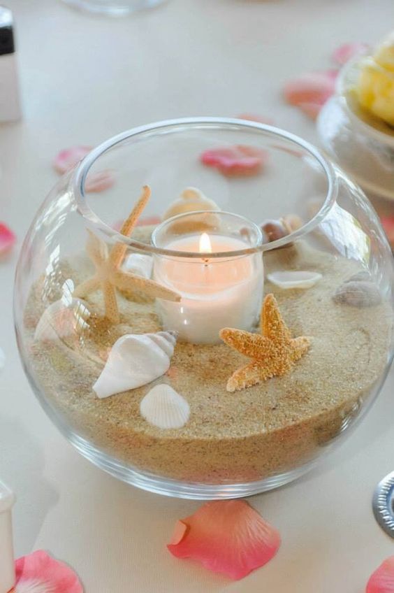 a glass bowl with beach sand, shells, starfish and a blush candle is a perfect fit for a beach wedding