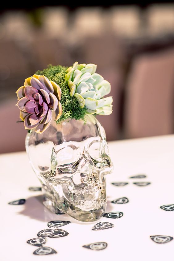 a transparent skull vase with moss and succulents for a cool wedding centerpiece
