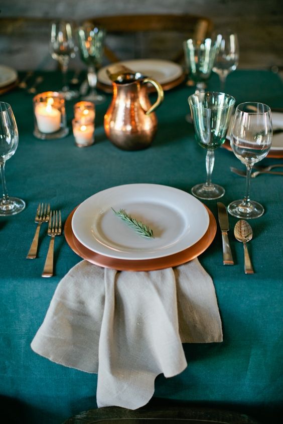 a teal tablecloth and glasses, copper chargers and jugs look chic