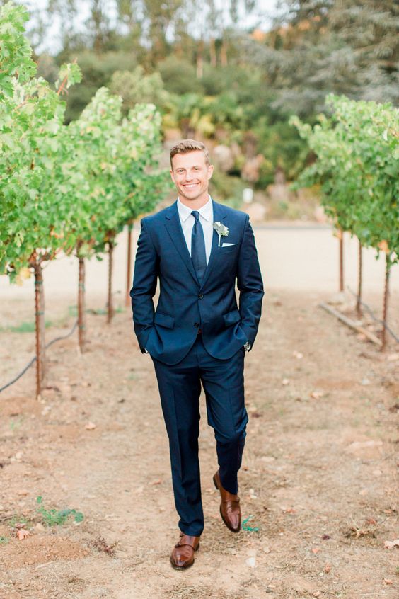 a navy two piece wedding suit with a matching tie and cognac shoes