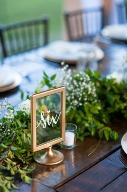framed copper table number and a lush greenery table runner