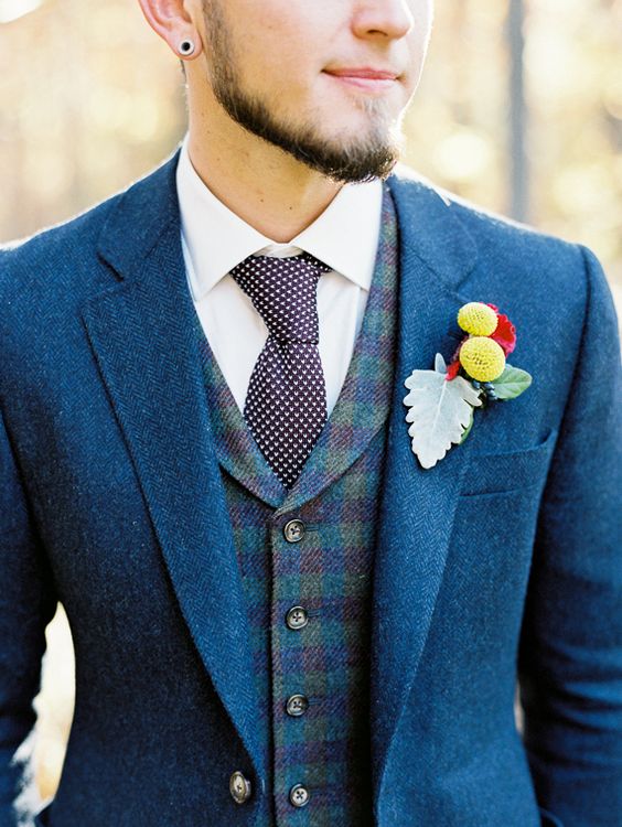 a bold blue suit, a checked vest and a knit printed tie