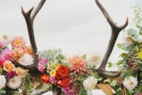 17 a bold floral wedding arch with a skull and antlers for a boho feel