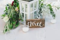 17 a wooden and metal candle lantern, a wooden table number and a beautiful floral and greenery arrangement