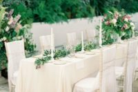 17 gorgeous neutral wedding reception with a greenery table garland and gold details on a castle terrace