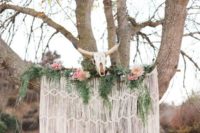 18 a macrame wedding backdrop with ferns, pink roses and an animal skull