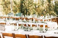 19 wedding reception with greenery table runners, candles and wooden chairs