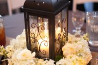 20 a dark metal candle lantern in a box with white floral arrangements for a rustic tablescape