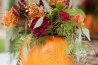 20 a pumpkin vase with a colorful floral and greenery arrangement as a fall wedding centerpiece