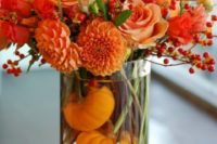 21 a bold floral arrangement in burnt orange and pumpkins in the vase for a fall wedding