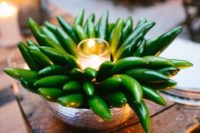a silver bowl centerpiece with green peppers and a candle is a way to get a different look, great for fall weddings