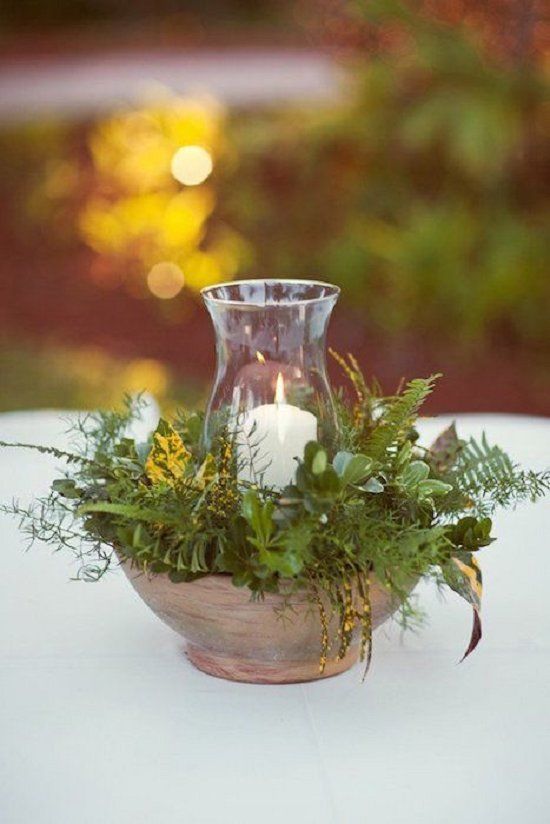 a bowl filled with greenery and herbs and a candle in the center for a woodland wedding