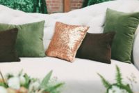22 a cozy wedding lounge with emerald and copper glitter pillows, a green glass vase and ferns