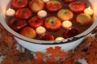 23 a metal bath with floating candles and apples surrounded with fall leaves is a chic idea for a rustic wedding