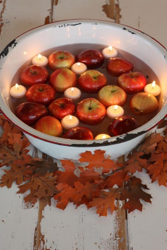 a metal bath with floating candles and apples surrounded with fall leaves is a chic idea for a rustic wedding