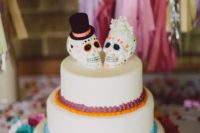 23 a wedding cake with colorful cream and sugar skull toppers