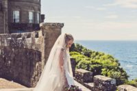 23 gorgeous bride in a refined dress and a veil standing on a castle wall