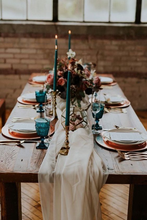 teal cnadles and glasses and copper chargers and flatware look very chic and embrace the fall