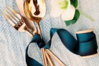 24 copper flatware tied with a teal ribbon for an elegant table setting