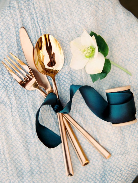 copper flatware tied with a teal ribbon for an elegant table setting
