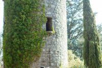 26 a couple portrayed in front of a castle tower covered with lush greenery looks intimate and heavenly