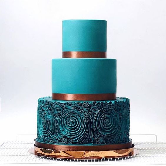 a teal wedding cake with a ruffle rose layer and copper ribbons