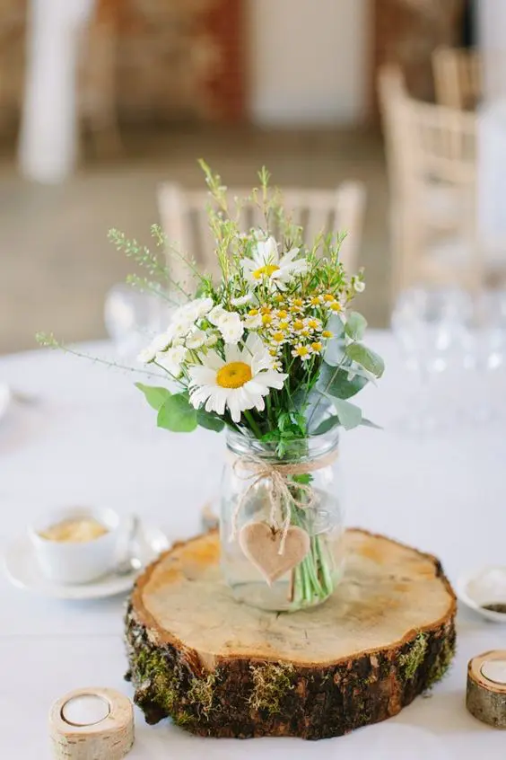 a wood slice with a jar, a wooden heart and wildflowers will be great for a summer wedding