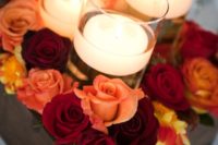 30 a dark stained box with red and orange roses and floating candles in tall glasses