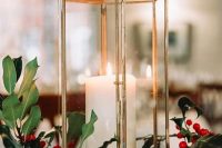 a Christmas wedding centerpiece of a candle lantern, greenery and berries is a catchy and cool idea
