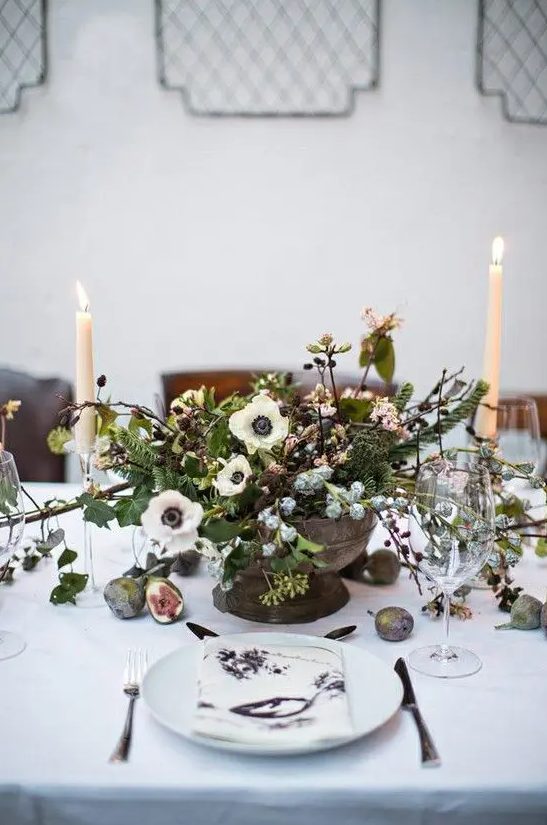a beautiful and natural wedding centerpiece with textural greenery, evergreens, anemones and berries plus candles for a Scandinavian winter wedding