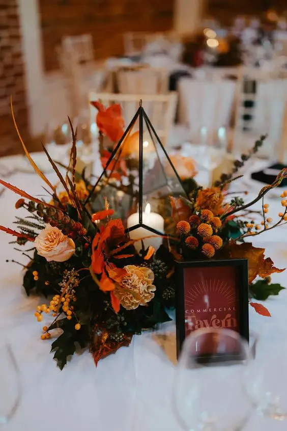 a beautiful fall lantern wedding centerpiece with super bold blooms, greenery and berries is gorgeous for the fall