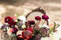 a bold rustic fall wedding centerpiece of red, fuchsia, deep purple, blush blooms, artichokes and some eucalyptus is a sumptuous idea