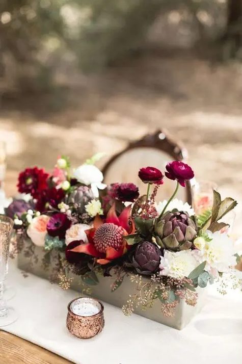 a bold rustic fall wedding centerpiece of red, fuchsia, deep purple, blush blooms, artichokes and some eucalyptus is a sumptuous idea