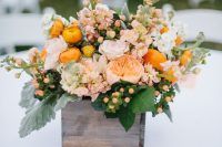 a bold summer wedding centerpiece of a wooden box with blush and orange blooms, berries and leaves