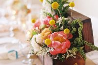a bold wedding centerpiece of a stained box with greenery, bright blooms and billy balls is a cool idea