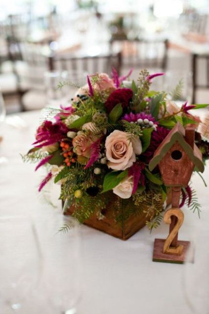 a bold wedding centerpiece of a wooden box, blush and fuchsia blooms, greenery and seed pods is amazing