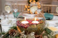 a bowl with floating candles and cranberries plus evergreens and pinecones for a lovely Christmas wedding