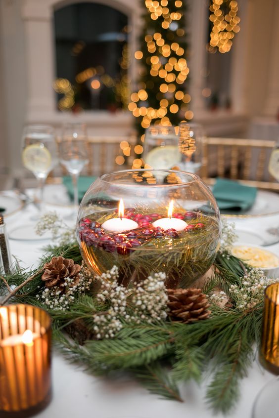 a bowl with floating candles and cranberries plus evergreens and pinecones for a lovely Christmas wedding