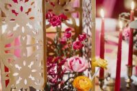 a bright Moroccan wedding centerpiece of a carved lantern and bold blooms is really amazing and bold