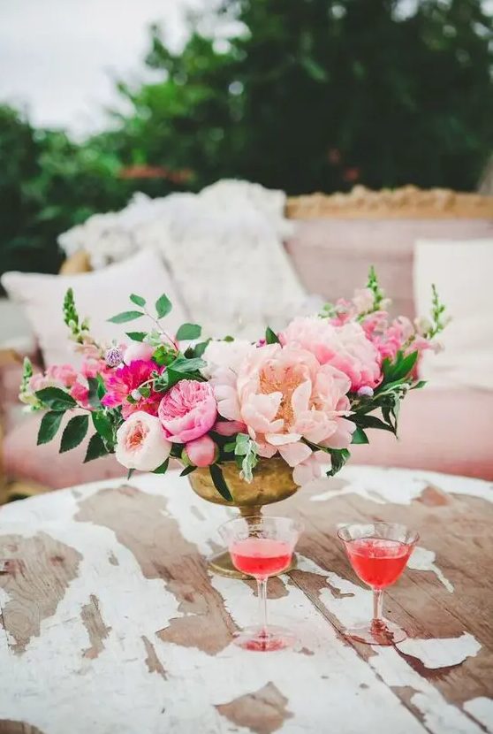 a bright floral centerpiece with blush, pink and hot pink flowers plus greenery