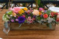 a bright rustic wedding centerpiece of a wooden box with bold blooms and greenery is a super stylish and catchy idea