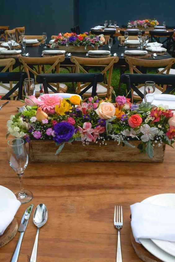 a bright rustic wedding centerpiece of a wooden box with bold blooms and greenery is a super stylish and catchy idea