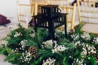 a candle lantern surrounded with evergreens, pinecones and baby’s breath is a simple idea for Christmas