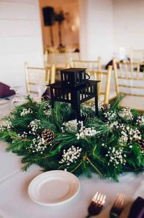 a candle lantern surrounded with evergreens, pinecones and baby's breath is a simple idea for Christmas