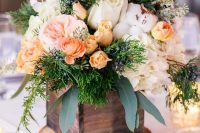 a catchy rustic wedding centerpiece of a tree slice, a stained wooden box with white and pastel blooms and greenery