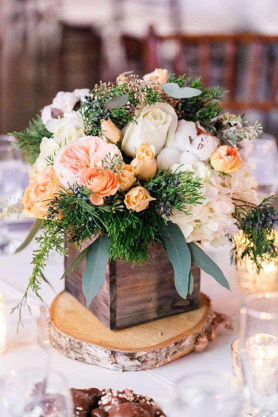 a catchy rustic wedding centerpiece of a tree slice, a stained wooden box with white and pastel blooms and greenery