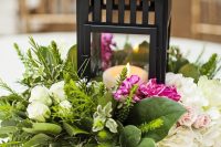 a catchy wedding centerpiece of a wooden box with white and pink blooms, greenery and a candle lantern for a vintage-inspried wedding